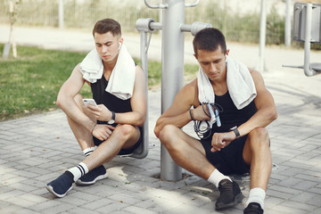Fototapeta na wymiar Men in a city. Guys in a sports clothes. Male with phone and headphones