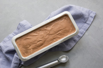 Banana chocolate homemade ice cream in container on grey. Space for text. Top view.