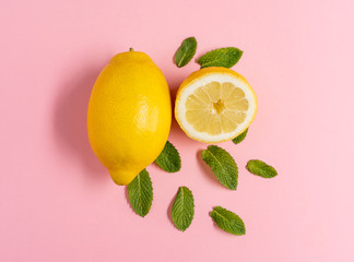 Zenith image of a lemon and a half with mint leaves on a pink background with