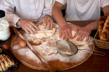  bakers hands kneading the dough on the table