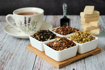 Detail of a mug with red tea, dry tea leaves and wafer biscuits