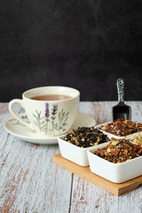 Detail of a mug with red tea and dry tea leaves. Copy space with dark background