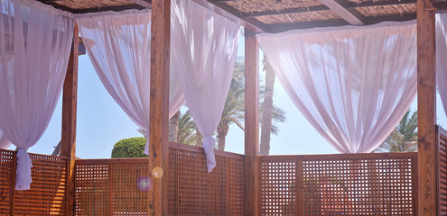 Sheds awning with fabric white curtains on the seashore breeze in the wind