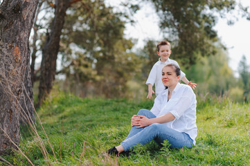 Fototapeta premium Stilish mother and handsome son having fun on the nature. Happy family concept. Beauty nature scene with family outdoor lifestyle. Happy family resting together. Happiness in family life. Mothers day.