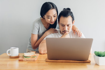Asian man is working online with his wife support in concept of work from home.