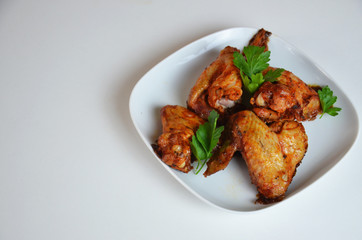 plate of chicken wings on white table red sauce in a gravy boat