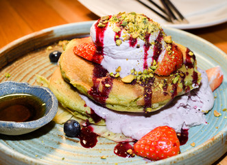 Matcha powder pancakes served in a restaurant setting, with ice cream, strawbberries and chocolate