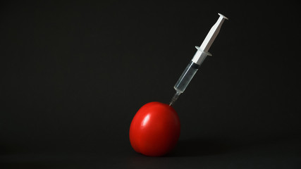 Syringe in a tomato on a black background