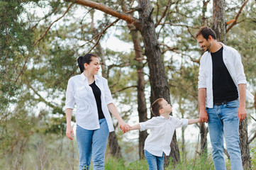 Naklejka na ściany i meble Dad, mom and little son having fun together, outdoors. Family walk in park. Happy family outdoors. Family, vacation concept