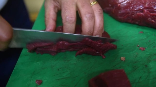 Un cuisinier d&eacute;coupe un steak hach&eacute; au couteau