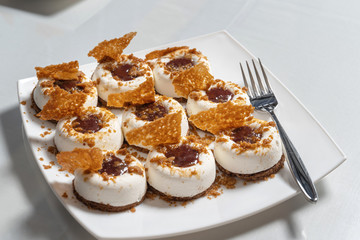 Mousse cake with jam and cookies. On a white plate.