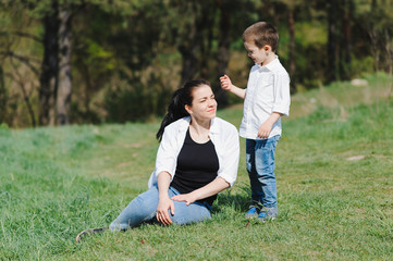 Stilish mother and handsome son having fun on the nature. Happy family concept. Beauty nature scene with family outdoor lifestyle. Happy family resting together. Happiness in family life. Mothers day.