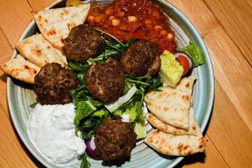 Mediterranean meatballs with salad, chickpeas with tomato sauce, yogurt dip and pita bread