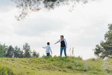 Fototapeta premium Stilish mother and handsome son having fun on the nature. Happy family concept. Beauty nature scene with family outdoor lifestyle. Happy family resting together. Happiness in family life. Mothers day.