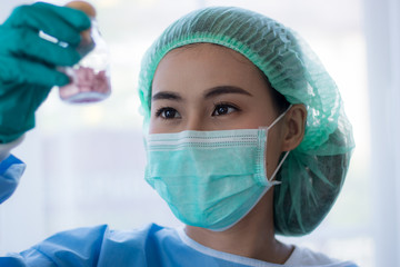 Asian Young woman scientist looking through a microscope in a laboratory. Young scientist doing...