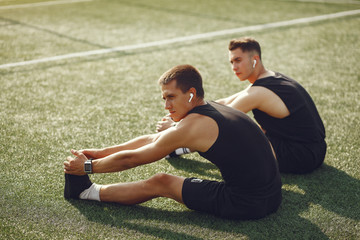 Men in a city. Guys in a sports clothes. Friends training on a grass