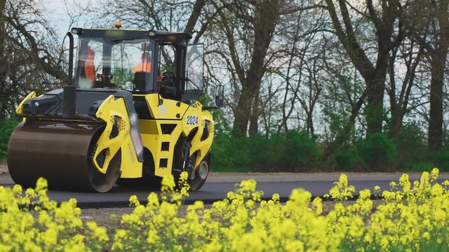 Roller machines make new asphalt roads. The asphalt paver squeezes hot asphalt.