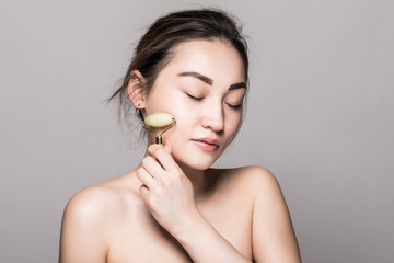 Portrait of happy young asian woman taking care of her skin and doing massage with cosmetology...