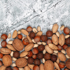 Mix of raw inshell nuts on gray stone background
