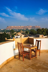 Rooftop Table with chairs with view of tourist landmark of Rajasthan - Jaisalmer Fort known as the Golden Fort Sonar quila, Jaisalmer, Rajasthan, India