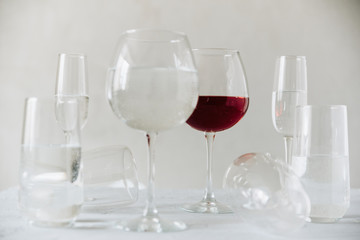 glass clear glasses with water and one glass of wine on a gray background