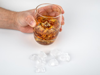 Glass of whisky and ice cubes on white background