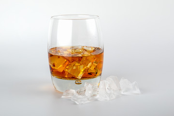 Glass of whisky and ice cubes on white background