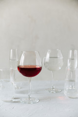 glass clear glasses with water and one glass of wine on a gray background