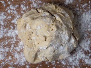 Raw dough covered with flour on a wooden cutting board.