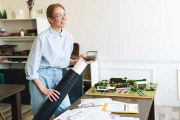 Photo of woman architect working with drawings while designing draft
