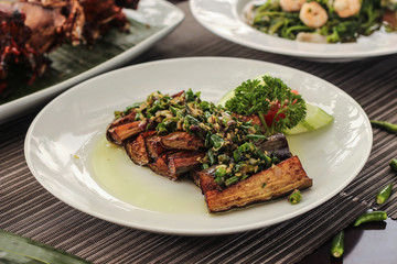 spicy balinese fried eggplant on a white plate and blurred background