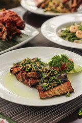 spicy balinese fried eggplant on a white plate and blurred background