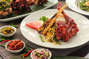 grilled chicken Balinese sauce with chicken satay and vegetable. Indonesian cuisine on white plate