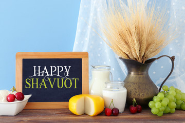 photo of dairy products over old wooden table and pastel background. Symbols of jewish holiday - Shavuot