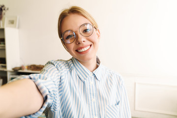 Photo of happy blonde woman smiling while taking selfie photo