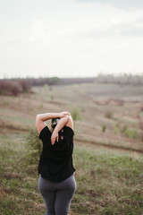 Overweight woman stretching hands while walking outdoors. Flexibility, healthy joints and workout