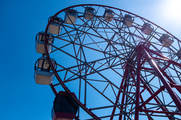 Ferris wheel on a background of clear blue sky. Bright sunny day. The concept of relaxation and entertainment.