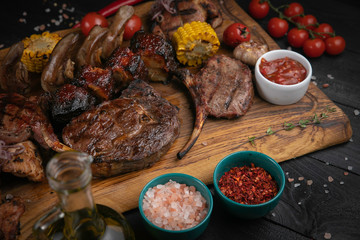 Assorted delicious grilled meat with vegetable and herbs on rustic table
