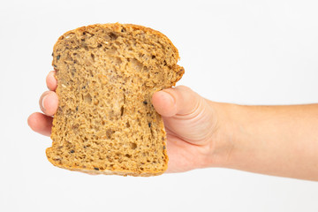 One slice of cereal loaf in female hand. Piece of baked at home bread made of rye flour isolated on white background. Studio shot. Top view. Homemade food and nutrition concept