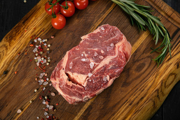 Chef prepare steak. Uncooked steak in sauce with spices an rosemary on a old wooden desk.