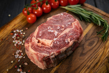 Chef prepare steak. Uncooked steak in sauce with spices an rosemary on a old wooden desk.