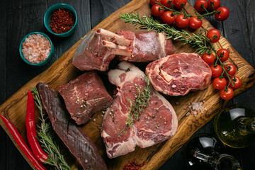 Chef prepare steak. Uncooked steak in sauce with spices an rosemary on a old wooden desk.