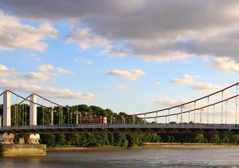 Keuken spatwand met foto A view of a suspension bridge with a red bus crossing the river Thames, west London, United Kingdom. © Roksana