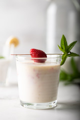 Banana and strawberry milkshake with mint leaves and berry garnish. Light  image, healthy and delicious breakfast concept