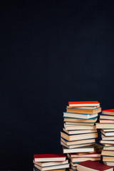 many stacks of educational books to prepare for exams in the university library black background