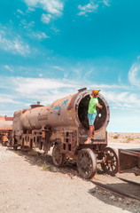 Tourist, Train Cemetry Bolivia Salt Flats. Bolivian salty desert and blue sky background. Shot in Salar de Uyuni. Rusted, waste, abandoned, locomotive graveyard, railroad concepts. Tourist attraction