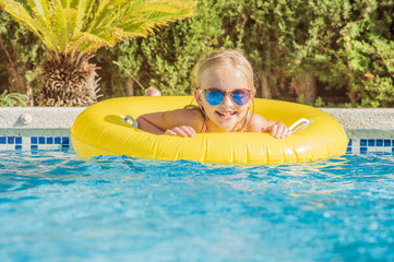Summertime fun. Pretty little girl swimming in outdoor pool