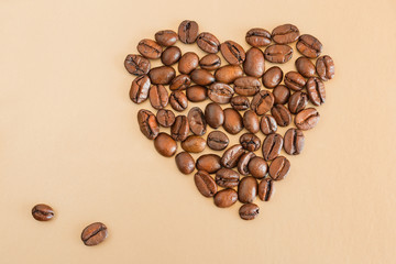 Coffee beans laid out in the shape of a heart on a beige Background with copy space . Love coffee.

