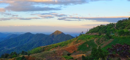 A beautiful green mountain range in Northern Thailand in the morning with winding along the side of the mountain.