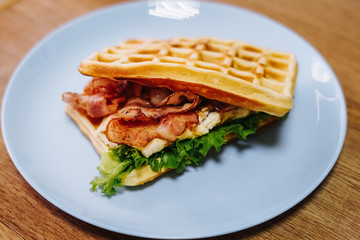 tasty Belgium waffle with lettuce, meat, egg and vegetables served of pretty blue plate
